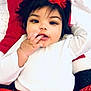 Remiyah is registered to the contest to win money with this photo: baby, blanket, child, closeup, cute, dark_hair, eyes, face, festive, hand, holiday_outfit, infant, lying_down, mouth, portrait, red_bow, red_dress, smile, toddler, white_top