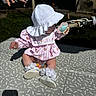 baby, child, hat, sun_hat, pacifier, pink_dress, white_shoes, socks, outdoor, grass, bicycle, mat, shadow, person, sitting, toy, summer, sunlight, playtime, relaxation