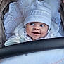 baby, child, smile, hat, pom_poms, stroller, white_clothing, lace, fabric, cozy, cute, face, infant, warm_clothing, portrait, happy, closeup, indoors, baby_boy, baby_girl