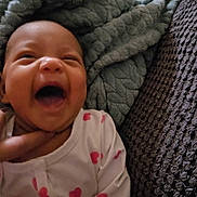 Izabella is registered to the contest to win money with this photo: baby, infant, smiling, laughing, blanket, pajamas, hearts, cozy, hand, couch, textured_blanket, happy, portrait, close_up, home_interior, lying_down, newborn, skin, facial_expression, sleepwear