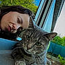 cat, gray_cat, tabby, pet, animal, whiskers, green_eyes, furry, sitting, paws, closeup, portrait, selfie, person, face, puckered_lips, window, outdoor, backyard, trees