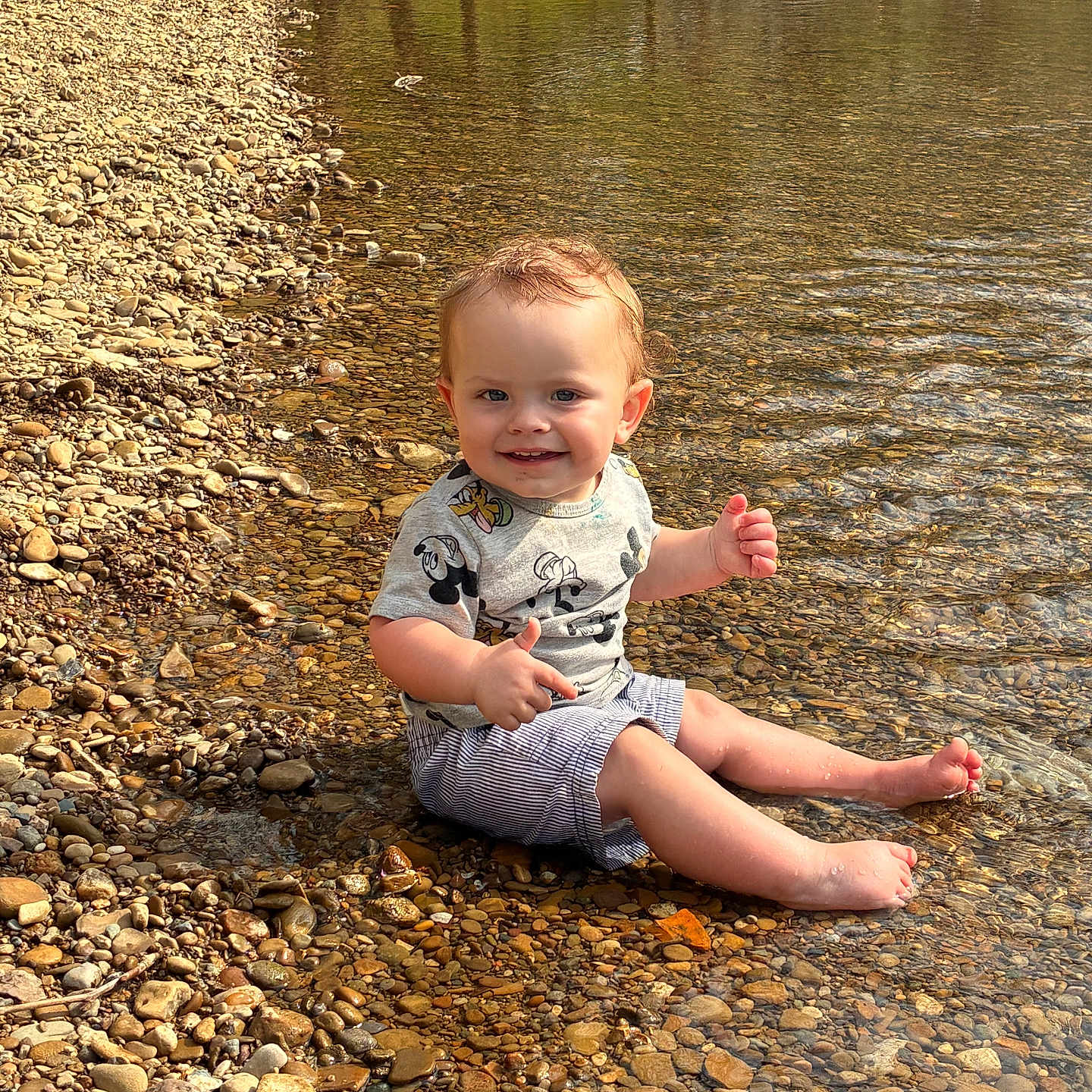 Gracen is registered to the contest to win money with this photo: toddler, child, water, stream, pebbles, smile, shirt, shorts, sunlight, outdoor, nature, happy, sitting, barefoot, playful, summer, reflection, person, riverbank, casual