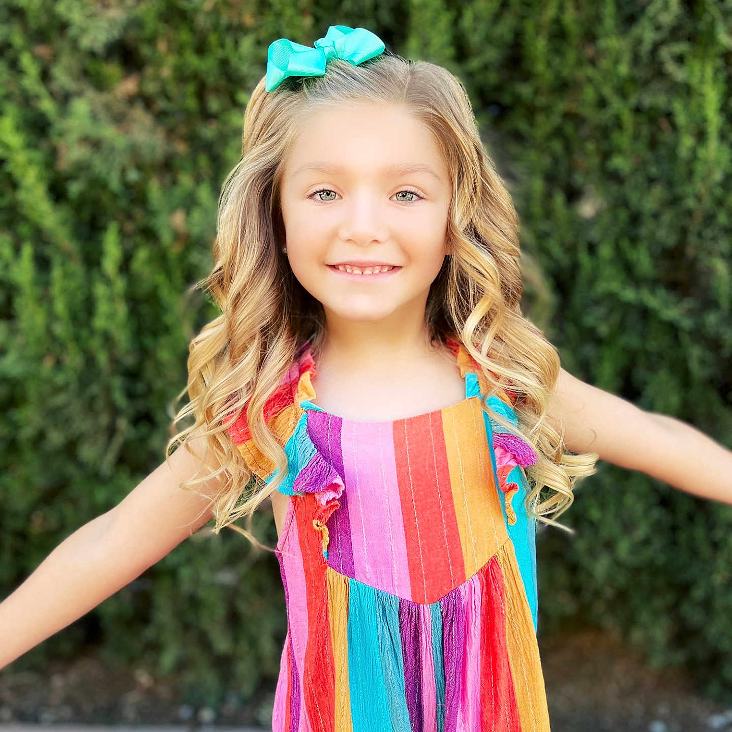 Velouria joined the competition — help win amazing prizes! arms_outstretched, blonde, bow, child, colorful_dress, curly_hair, cute, fashion, girl, greenery, happy, hedge, nature, outdoor, person, portrait, smiling, striped_dress, sunny, youth