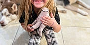 Velouria is registered to the contest to win money with this photo: child, smiling, blonde_hair, plaid_leggings, black_boots, doll, indoor, tiled_floor, dog, husky, pet, happy, seated, toy, casual_clothing, long_hair, floor, cute, cozy, portrait