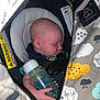 baby, infant, sleeping, bottle, car_seat, blanket, hand, face, child, clothing, comfort, cute, indoors, peaceful, rest, toddler, young_child, soft_lighting, close_up, protective_gear