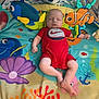 baby, infant, sleeping, onesie, red_clothing, play_mat, toys, fish_toy, colorful, indoor, carpet, child, cute, peaceful, soft, floor, baby_toys, marine_life, decor, relaxation