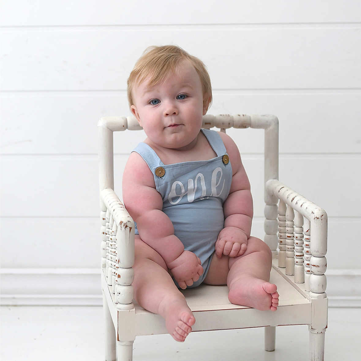 Rhett joined the competition — help win amazing prizes! baby, blonde_hair, blue_romper, child, chubby, curious, cute, expression, face, feet, hands, indoor, infant, minimalistic, plump, portrait, sitting, white_background, white_chair, wooden_chair