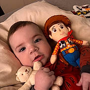Michael is registered to the contest to win money with this photo: baby, child, teddy_bear, stuffed_toy, woody_doll, pillow, indoor, bed, cute, portrait, infant, soft_lighting, red_clothing, hand, face, eyes, toy_story, plush, smile, cozy