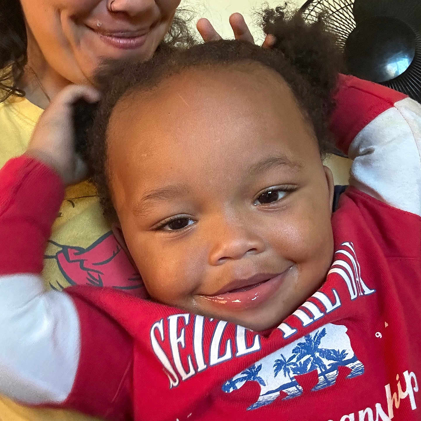 Kasaine is registered to the contest to win money with this photo: adult, casual, child, closeup, curly_hair, cute, expression, face, family, fan, hand, happy, indoor, joy, person, playful, portrait, red_sweater, smile, yellow_shirt