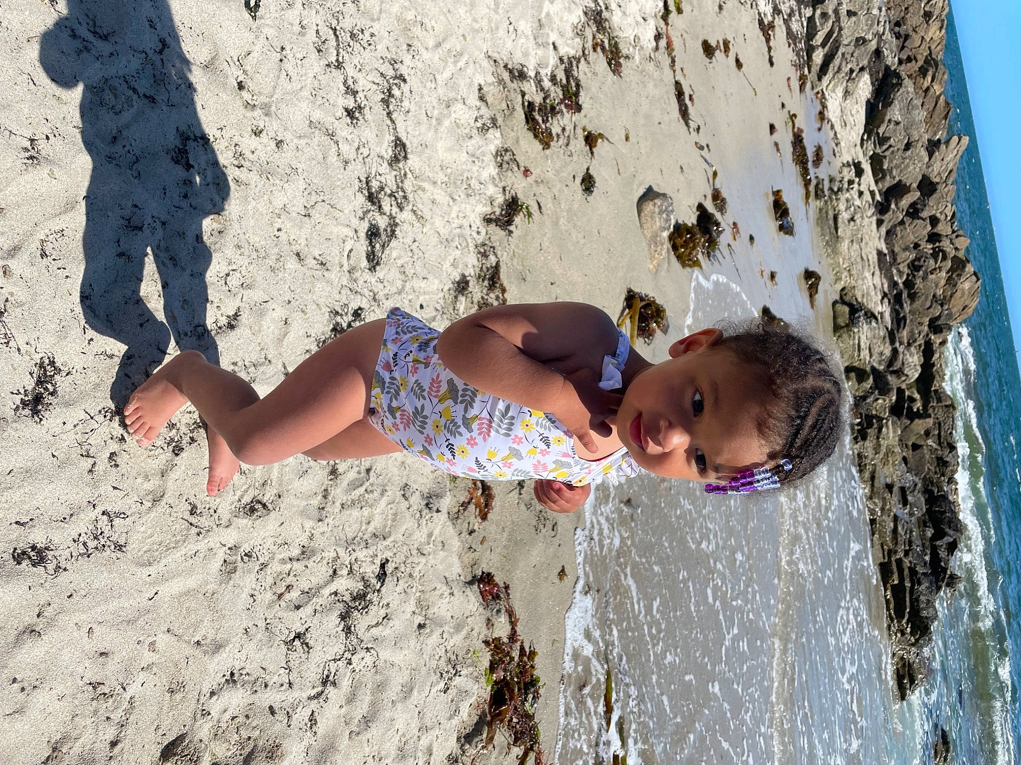 Kélya a rejoint le concours — aidez-le/la à gagner de superbes lots ! beach, coast, foot, fun, happy, human_leg, landscape, leg, leisure, people_in_nature, person, recreation, rock, sand, shorts, summer, thigh, toddler, wall, water