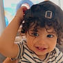 toddler, child, smiling, curly_hair, cap, striped_shirt, indoor, face, happy, person, portrait, cute, baby, hand, eyes, cheerful, young_child, headwear, couch, background