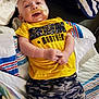 baby, smiling, yellow_tshirt, awesome_brother, camo_pants, towel, medical_tape, indoor, lying_down, child, cute, happy, infant, face, person, skin, clothing, fabric, baby_boy, casual