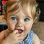 baby, blond_hair, blue_eyes, child, close_up, curious, curly_hair, cute, expression, face, finger_in_mouth, hand, indoor, person, portrait, skin, sleeveless_top, striped_clothing, toddler, young_child