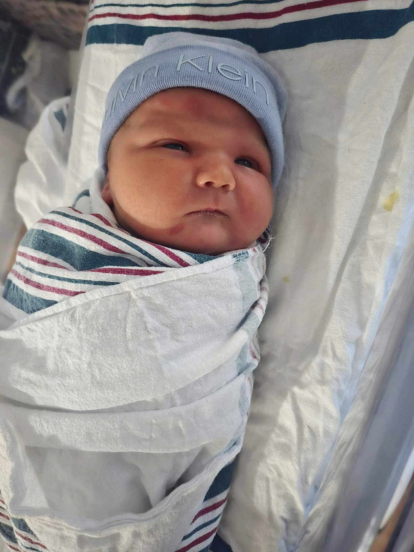 Samuel is registered to the contest to win money with this photo: newborn, baby, infant, wrapped, blanket, hat, calvin_klein, hospital, bed, face, headwear, swaddled, cute, child, person, sleepwear, resting, soft, indoors, portrait