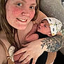 woman, baby, tattoo, hat, smile, closeup, indoor, person, skin, hand, face, newborn, holding, caring, love, clothing, portrait, babywearing, happy, cute