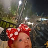 baby, infant, child, portrait, close_up, face, wide_eyed, outdoor, night, street_lights, bow, headband, red, polka_dots, sequins, black_clothing, being_held, adult, trees, background