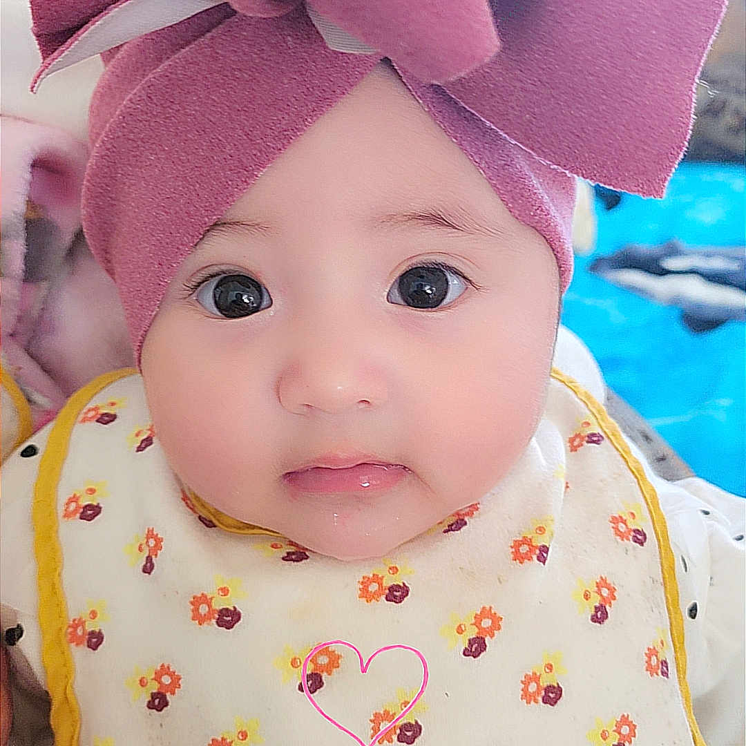 Khalia joined the competition — help win amazing prizes! baby, infant, face, headwear, pink_bow, bib, floral_pattern, cute, child, portrait, indoors, closeup, big_eyes, adorable, young_child, clothing, expression, skin, person, babywearing