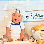 Ethan joined the competition — help win amazing prizes! baby, chef_hat, apron, flour, kitchen, baking, bread, croissant, rolling_pin, smiling, happy, infant, countertop, white_tiles, sign, cooking, cute, messy, child, portrait