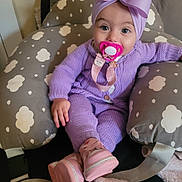 Suzanna is registered to the contest to win money with this photo: baby, infant, pacifier, purple_outfit, headwrap, bow, pink_boots, baby_seat, cloud_pattern, knitwear, cozy, cute, indoors, child, sitting, soft_toys, blanket, comfort, portrait, young_child