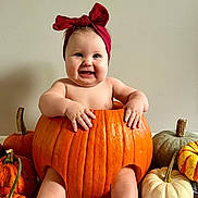Alexandra joined the competition — help win amazing prizes! baby, pumpkin, red_bow, smiling, autumn, holiday, cute, child, orange, white_pumpkin, green_pumpkin, decor, festive, sitting, indoors, headwear, happy, skin, toes, hands