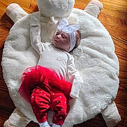 Clara joined the competition — help win amazing prizes! baby, infant, sleeping, headband, bow, red_pants, white_top, pacifier, plush_cushion, bear_shape, wooden_floor, cozy, cute, toddler, child, indoors, soft_texture, resting, peaceful, adorable