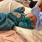 Magnolia is registered to the contest to win money with this photo: newborn, baby, pacifier, onesie, polka_dot, hat, bow, striped, sleeping, white_pillow, indoor, person, hand, clothing, cute, infant, resting, soft, closeup, bed