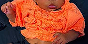 Brigette is registered to the contest to win money with this photo: baby, infant, child, orange_clothing, black_shorts, bow, striped_bow, socks, lying_down, portrait, cute, dark_background, smiling, face, hands, feet, newborn, curly_hair, adorable, closeup