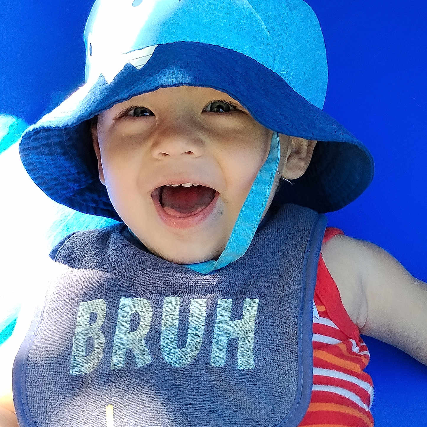 Constantine joined the competition — help win amazing prizes! baby, bib, blue_background, bucket_hat, child, clothing, cute, expression, face, happy, hat, infant, outdoor, playful, portrait, smiling, striped_shirt, summer, sunlight, toddler