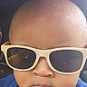 baby, bald, blue_shirt, car_interior, casual, child, closeup, cool, expressionless, eyewear, face, fashion, head, indoor, person, portrait, seat, skin, sunglasses, young_child