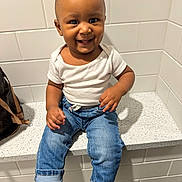 Karter joined the competition — help win amazing prizes! baby, bag, blue_jeans, casual_clothing, child, countertop, cute, face, footwear, hand, happy, indoor, person, portrait, sitting, smiling, socks, tile_wall, toddler, white_shirt