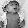 Mike is registered to the contest to win money with this photo: baby, infant, hat, striped_hat, shirt, open_shirt, lying_down, hand, mouth_open, black_and_white, portrait, cute, soft_light, skin, newborn, expression, child, young_child, closeup, face