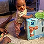 Dieu-Donné is registered to the contest to win money with this photo: toddler, child, diapers, box, carpet, indoor, person, television, adult, tattoo, clothing, standing, hand, foot, furniture, living_room, baby_wipes, expression, home, curious