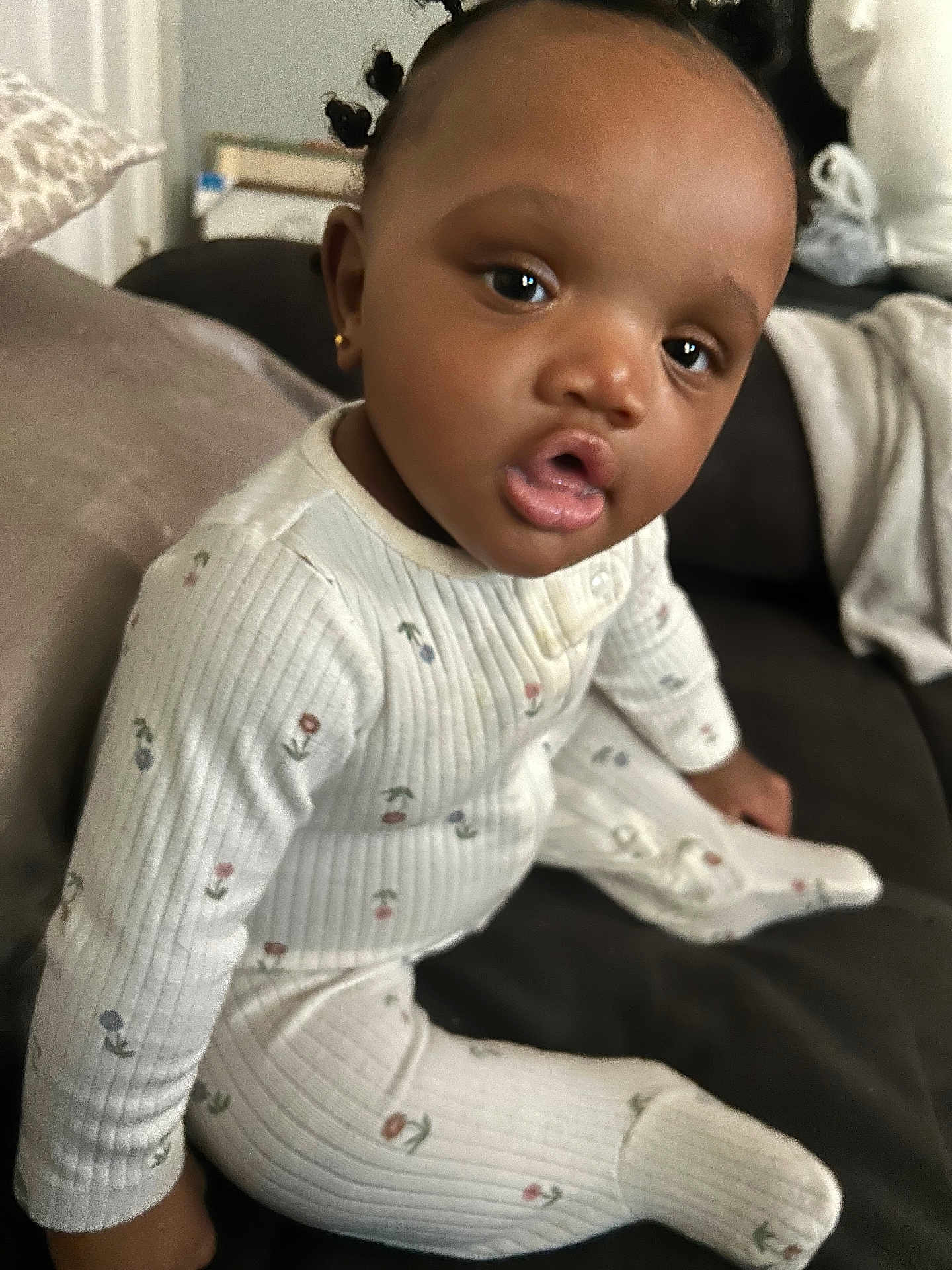 Dieu-Donné is registered to the contest to win money with this photo: baby, child, pajamas, sitting, indoors, face, curly_hair, earrings, couch, blanket, home, cozy, cute, expression, infant, person, clothing, comfortable, portrait, furniture