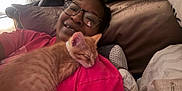 Dogg joined the competition — help win amazing prizes! person, cat, kitten, sleeping, glasses, pink_shirt, bed, pillow, cuddle, closeup, indoor, happy, resting, orange_cat, comfort, casual, portrait, relaxation, cute, domestic_animal