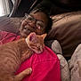 person, cat, kitten, sleeping, glasses, pink_shirt, bed, pillow, cuddle, closeup, indoor, happy, resting, orange_cat, comfort, casual, portrait, relaxation, cute, domestic_animal