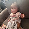 Nylah joined the competition — help win amazing prizes! baby, infant, couch, blanket, bib, clothing, indoor, person, child, seated, expression, face, curious, natural_light, home, comfort, soft_texture, casual, cute, young