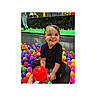 child, toddler, ball_pit, colorful_balls, smiling, black_clothing, indoor, play, happy, person, toy, reaching, sitting, fun, bright_colors, young_child, entertainment, cute, joy, leisure