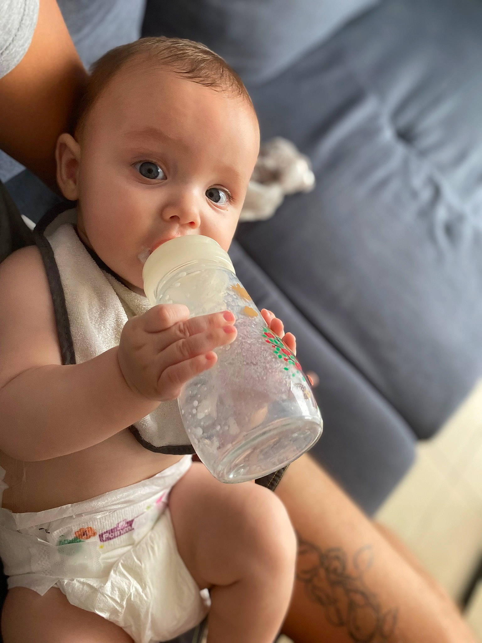 Milo a rejoint le concours — aidez-le/la à gagner de superbes lots ! baby_bottle, baby_toddler_clothing, cheek, couch, drinking, drinkware, eye, finger, happy, head, human_body, joint, leg, lip, mouth, nail, nose, person, plastic_bottle, skin