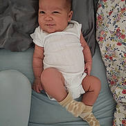 Elisha joined the competition — help win amazing prizes! baby, infant, onesie, socks, bed, blanket, floral_pattern, smile, face, skin, lying_down, clothing, cute, child, young, resting, indoors, fabric, soft, comfortable