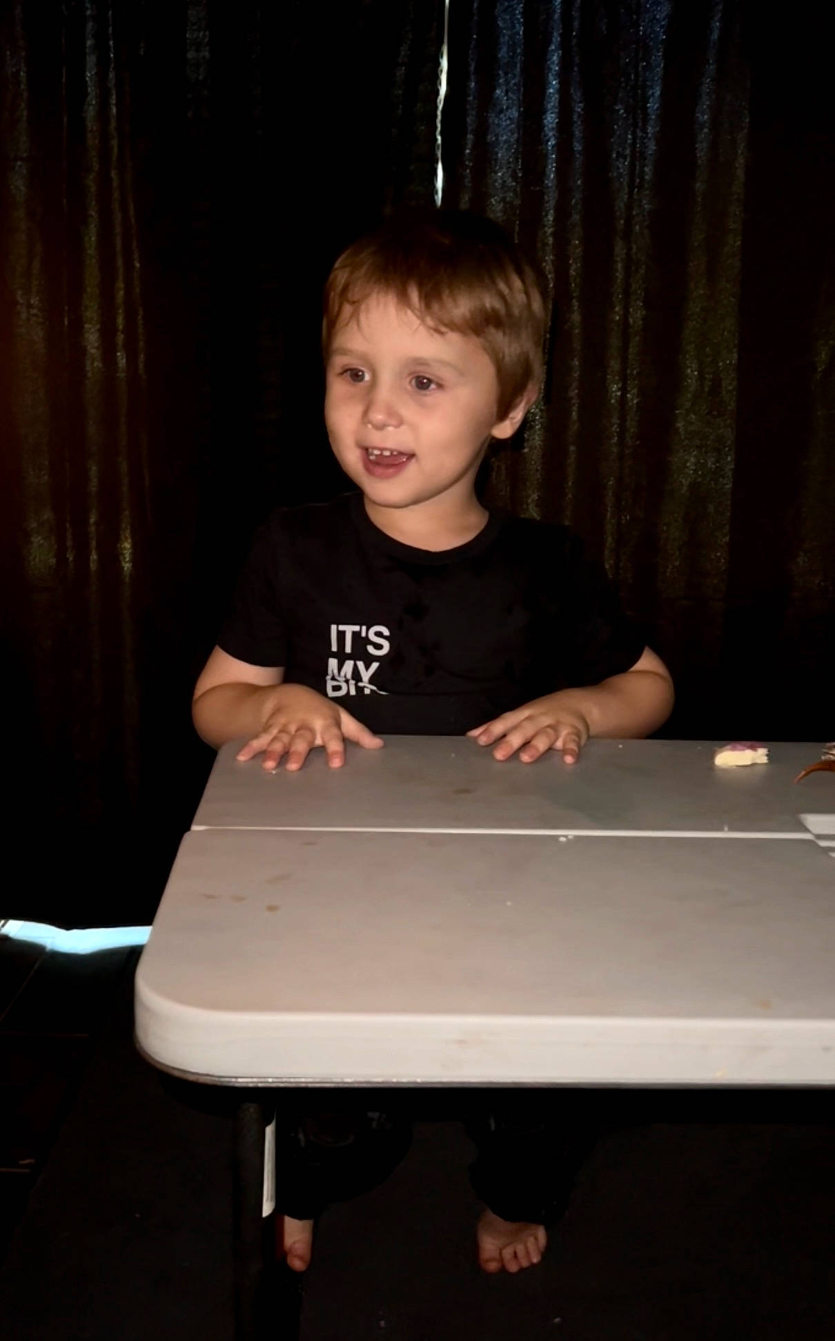 Corbin joined the competition — help win amazing prizes! composite_material, curtain, darkness, elbow, event, flash_photography, flooring, fun, person, rectangle, room, sitting, smile, standing, t_shirt, table, toddler, wood