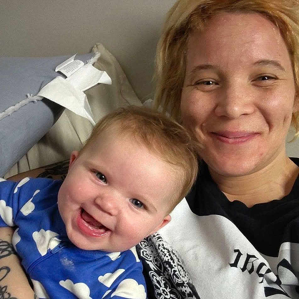 Preszley joined the competition — help win amazing prizes! adult, baby, blanket, blond_hair, cheeks, closeup, cloud_pattern, couch, eyes, face, infant, laughing, living_room, onesie, pillow, portrait, skin, smiling, tattoo, woman