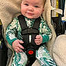 baby, blue_eyes, buckle, car_seat, child, chubby_cheeks, close_up, cute, fabric_texture, fleece_blanket, hand, harness, infant, leaf_pattern, onesie, portrait, seatbelt, short_hair, smile, warning_label