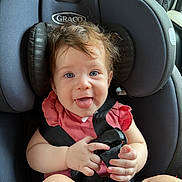 Daysha is registered to the contest to win money with this photo: baby, child, car_seat, seatbelt, blue_eyes, pink_clothing, hair, tongue, hand, infant, smiling, sitting, safety, child_seat, cute, indoors, car, portrait, person, happy