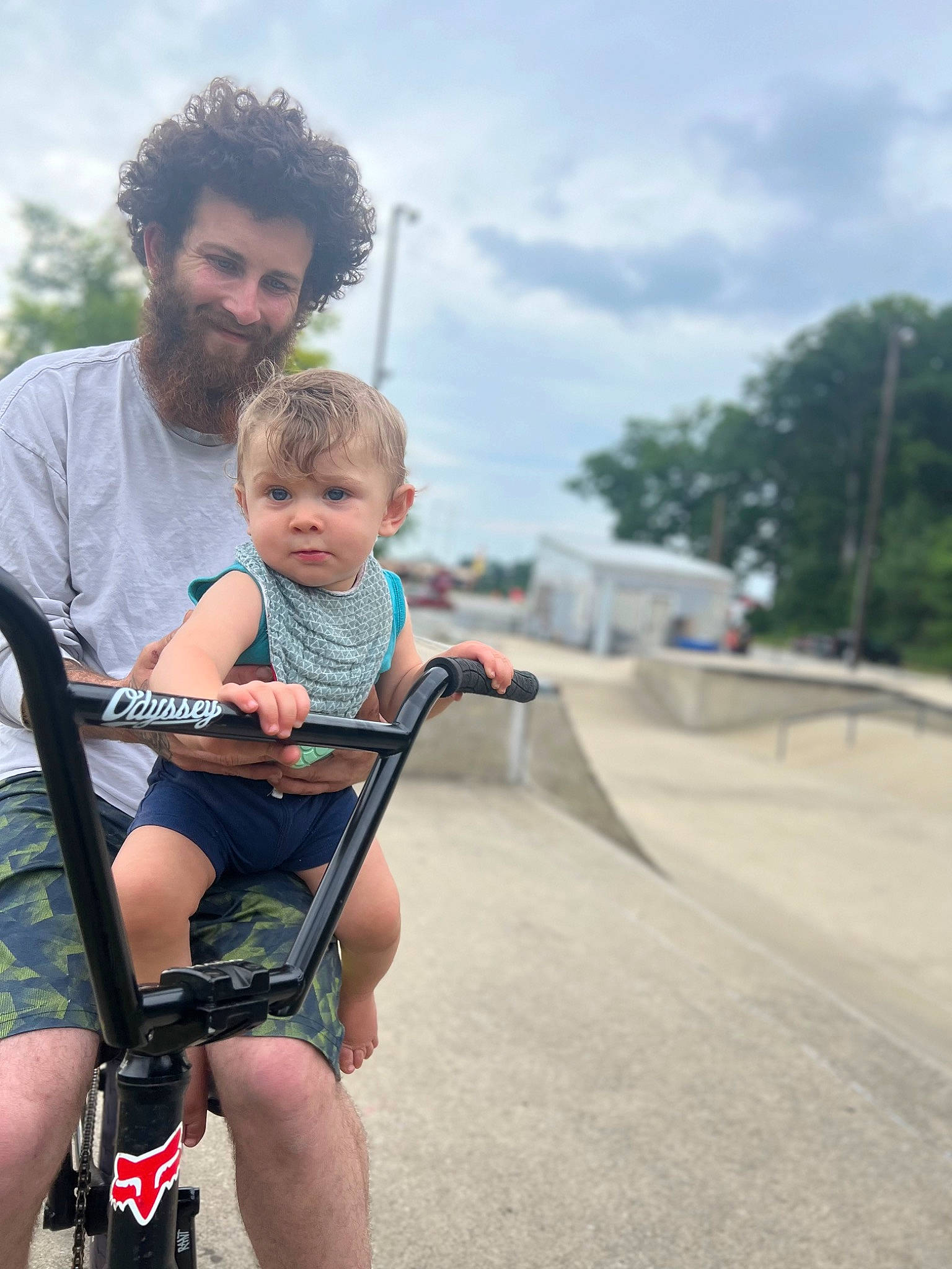 Liam is registered to the contest to win money with this photo: baby, baby_carriage, bicycle_fork, bicycle_frame, bicycle_handlebar, bicycle_tire, bicycles_equipment_and_supplies, cloud, face, happy, head, joy, leisure, person, recreation, shorts, sky, sunglasses, tire, toddler