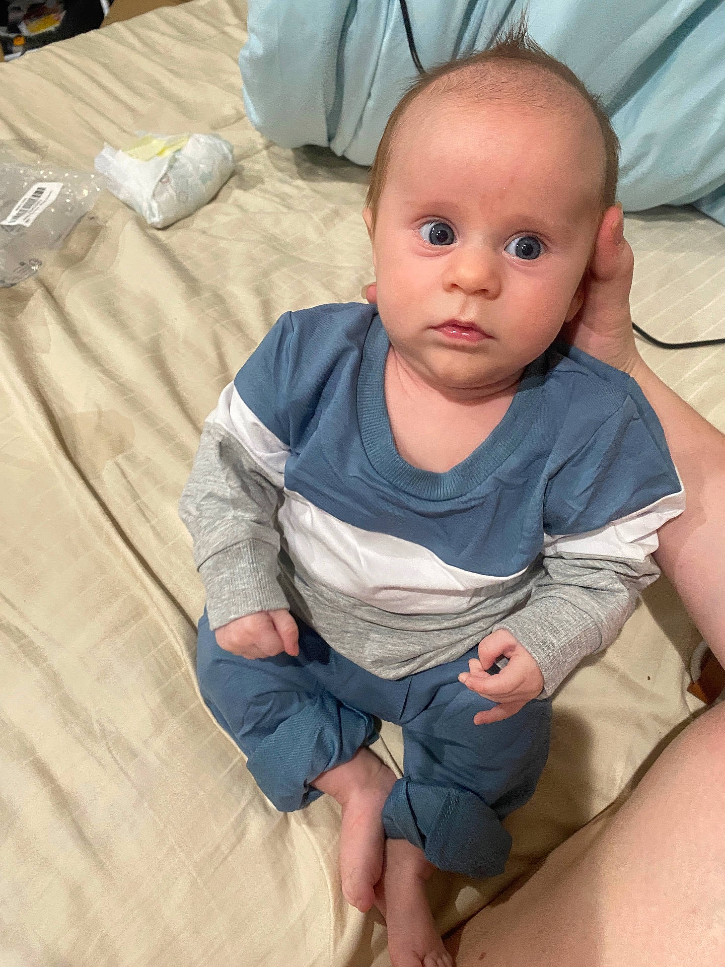 William is registered to the contest to win money with this photo: baby, barefoot, bed, bedroom, blue, casual, child, clothing, curious, diaper, eyes, face, gray, hand, indoor, infant, person, sheet, sitting, support