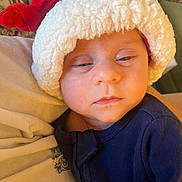 William is registered to the contest to win money with this photo: baby, infant, santa_hat, blue_clothing, sleepy, closeup, face, child, person, cozy, holiday, cute, indoors, soft_texture, warm, young, headwear, portrait, resting, newborn