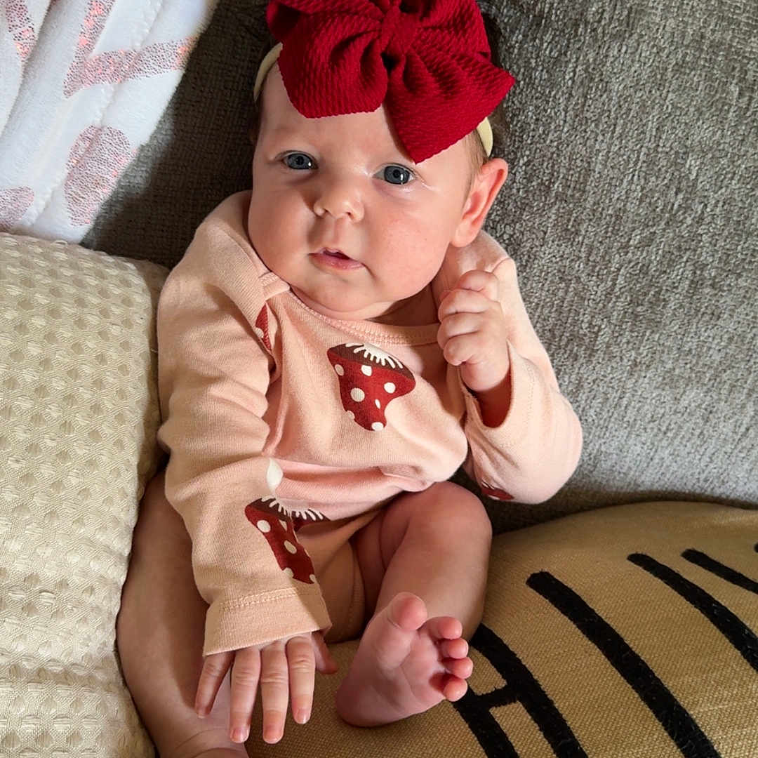Saylor Grace joined the competition — help win amazing prizes! baby, blanket, blue_eyes, child, clothing, couch, cozy, cute, expression, foot, hand, headband, indoors, infant, long_sleeves, pillows, portrait, red_bow, sitting, skin