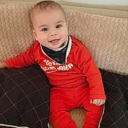 Charaf a rejoint le concours — aidez-le/la à gagner de superbes lots ! baby, bib, blanket, cheeks, couch, cozy, cute, eyes, face, happy, indoors, infant, photography, pillow, portrait, red_outfit, seated, smiling, socks, soft_texture