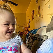 Lila joined the competition — help win amazing prizes! child, toddler, smiling, indoor, living_room, plush_toy, wall_decor, butterfly, ceiling_fan, couch, pillow, colorful_clothing, happy, person, portrait, home, furniture, cute, fun, light