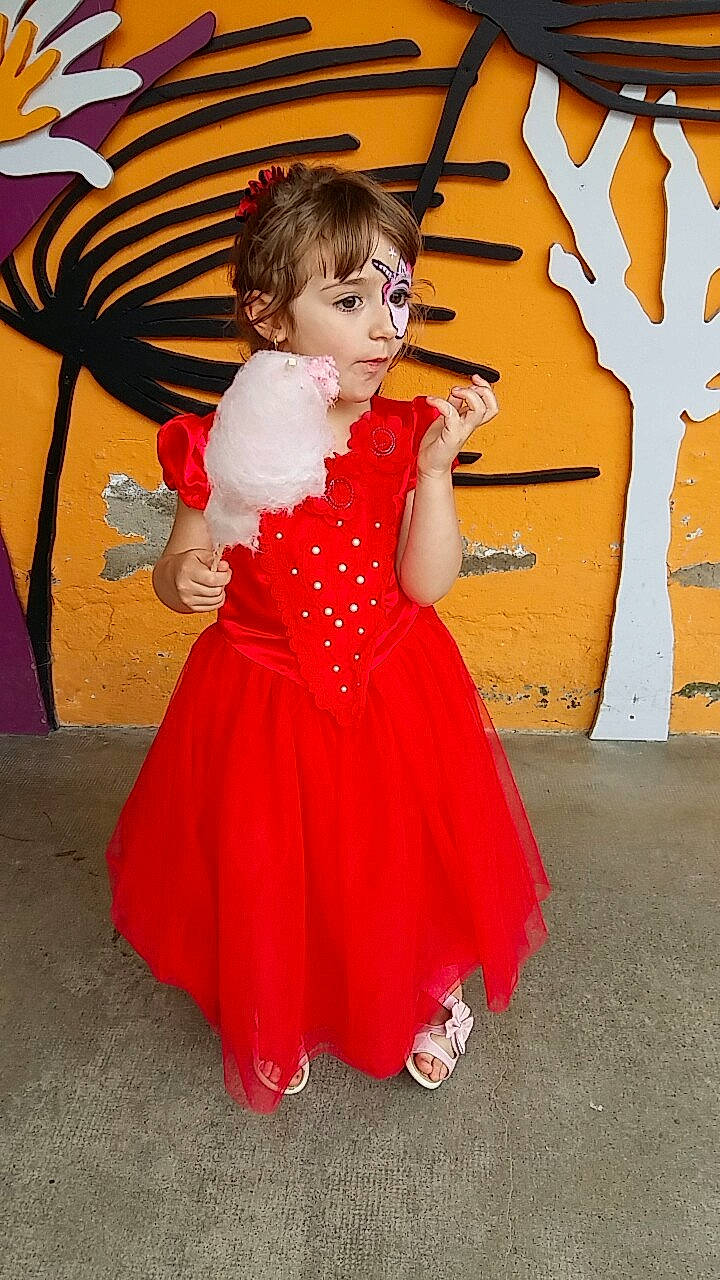 Louane participe au concours pour gagner de l'argent avec cette photo : carpet, child, clothing, costume, dress, flooring, formal_wear, fun, gown, joint, leg, person, red, shoulder, smile, toddler